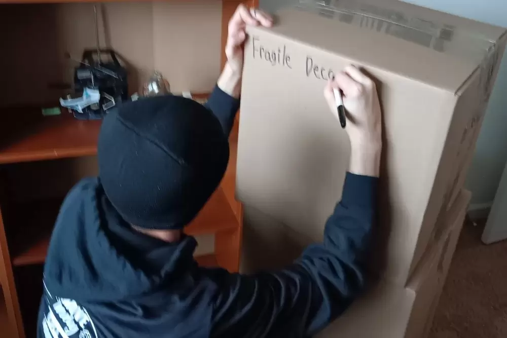Local Indianapolis mover from Move Indy labels a box after finishing packing it.